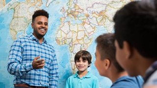 Image of person speaking to kids in front of map