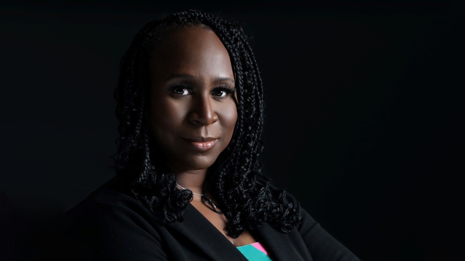 Photograph of Valenia Belle against a dramatic black background.