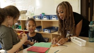 Yvonne Thevenot MAT ’14, founder/executive director of STEM Kids NYC, helps students explore mechanical engineering design. (PHOTO CREDIT: SHANNON SANDERS)