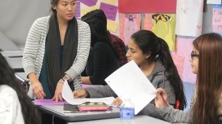 An instructor earns her California teacher salary while helping students with a lesson plan.