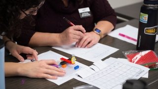 Two teachers work on a math problem using Legos during a Math for America LA professional development day.