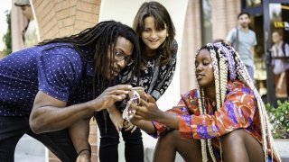 Two faculty members discuss their research on skateboarding with a student.