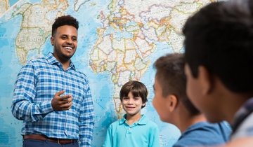 Image of person speaking to kids in front of map