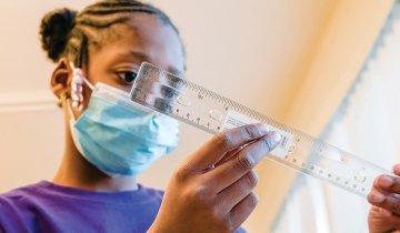 Autumn, a student in the Crenshaw Family YMCA’s after-school program, measures the structure she built for a bridge building challenge. (Photo/Rebecca Aranda)