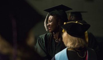 Two women dressed in caps and gowns at a graduation ceremony.