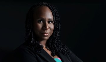 Photograph of Valenia Belle against a dramatic black background.