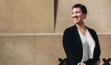 Portrait of Micki Smith standing in front of a sandstone building.