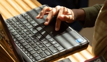 Image of a hand typing on a laptop computer.