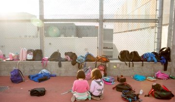 AMERICANED_UCLACOMM_041.jpg Two kindergarteners read together amid their classmates’ backpacks during an after-school program.