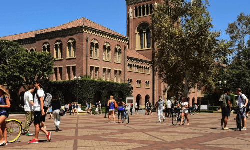 Students walking on campus with brown buildings behind them