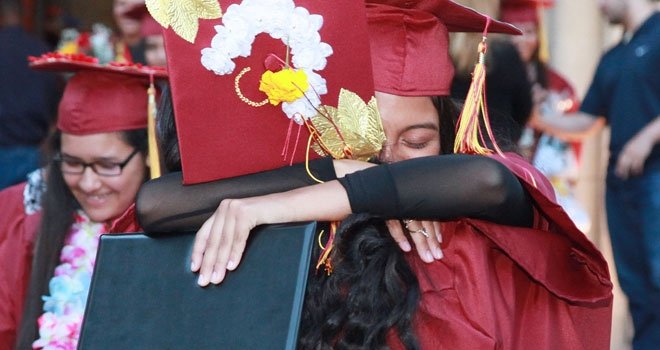 Students embrace after graduating from USC Hybrid High School. All seniors graduated and were accepted into at least one four-year college. Photo credit: Margaret Molloy for USC Rossier