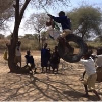 Children using the repaired swing at the Tanzanian School