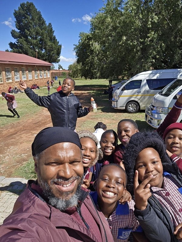 Professor Alan Green takes a photo with children from Dumezweni Elementary School.