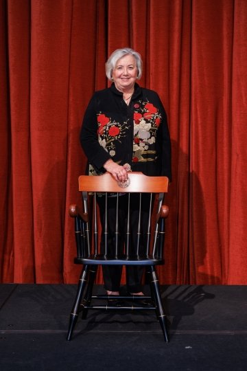 Photo of Maria Ott standing behind a chair.