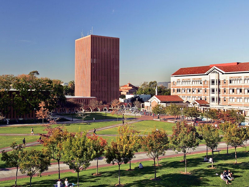 Aerial view of a university campus quad with a brick tower, historic buildings, and students walking among trees