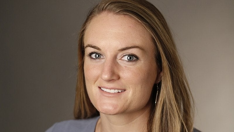 Headshot portrait of a smiling woman with long blonde hair against a neutral background