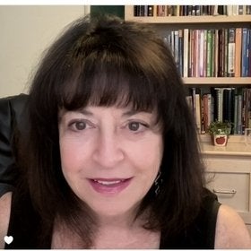 Headshot portrait of Rhoda Coleman smiling in front of a bookshelf