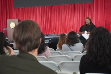 Kenae Danley at the front of an auditorium with students in the seats.