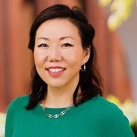 Headshot portrait of Kim smiling in a green top outdoors