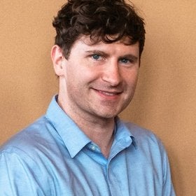 Headshot portrait of Kitchen smiling in a blue shirt