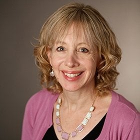 Headshot portrait of Krop smiling in a pink cardigan