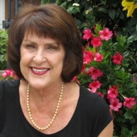 Headshot portrait of Smith smiling outdoors near flowers