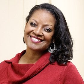 Headshot portrait of Tynes smiling in a red top
