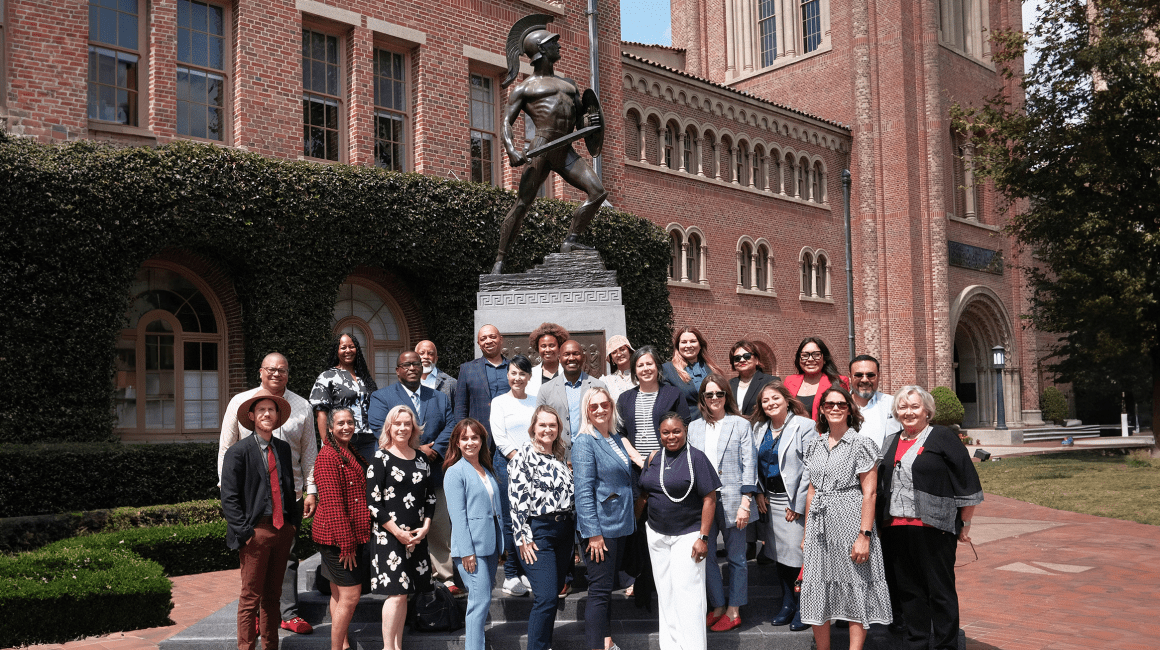 Large group of people posing in front of the Tommy Trojan statue at USC