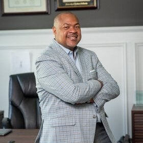 Portrait of Christopher Riddick smiling with arms crossed in an office