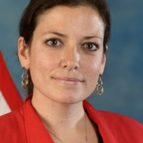Headshot portrait of Jennifer Phillips smiling in a red blazer