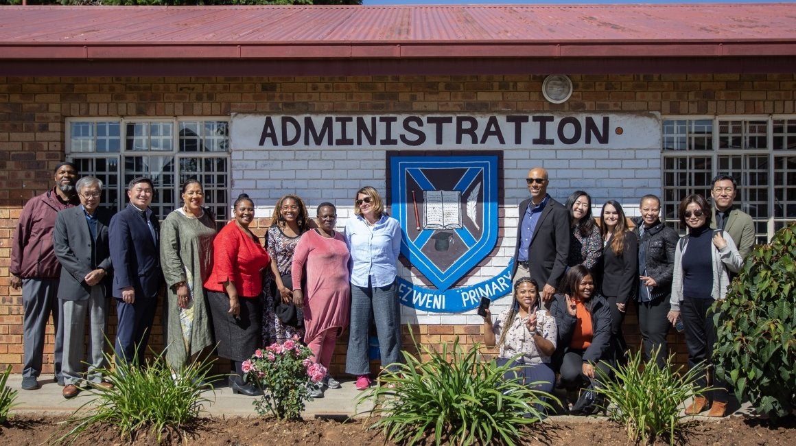 Group photo of USC Rossier faculty and staff posing outside a primary school administration building
