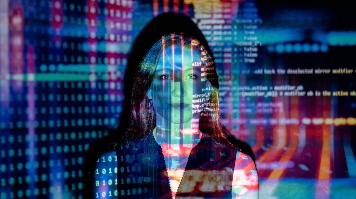 Double-exposure portrait of a woman's face overlaid with programming code and digital patterns