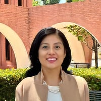 Professional headshot of a woman smiling outdoors near campus brick archways