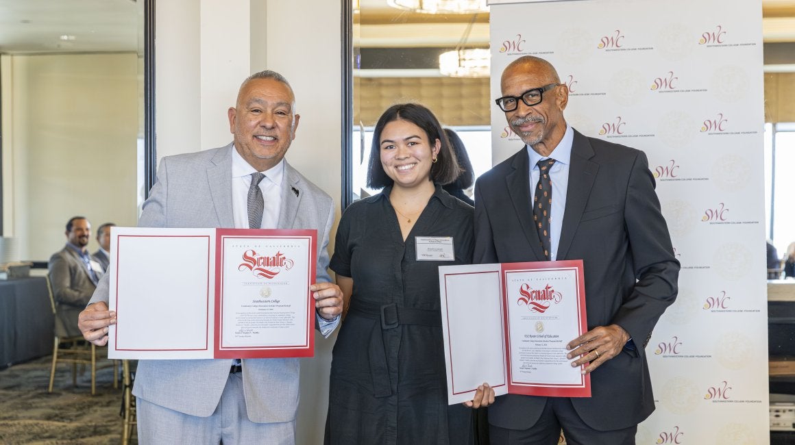 Three people holding certificate folders in front of a Southwestern College Foundation banner