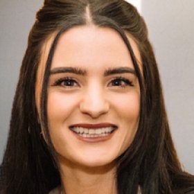 Headshot portrait of Danielle Silvaggio smiling against a gray background