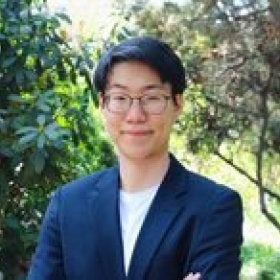Headshot portrait of Junmin Byon smiling outdoors with arms crossed