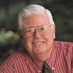 Headshot portrait of Gothold smiling in glasses and a plaid shirt