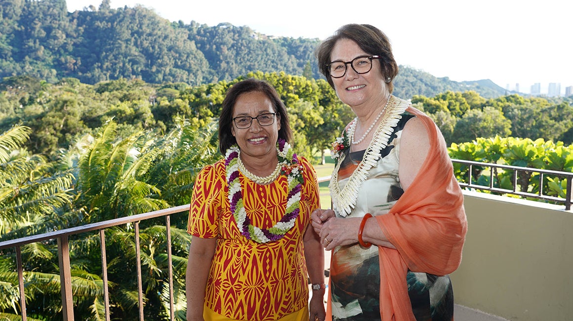 Two women standing on a balcony overlooking hills