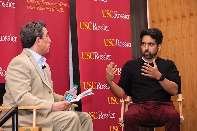 Two men speaking together on stage at a USC Rossier panel event