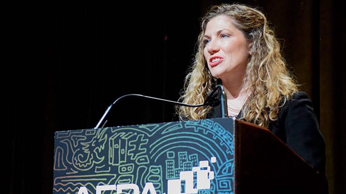Woman speaking at a podium during an AERA conference session