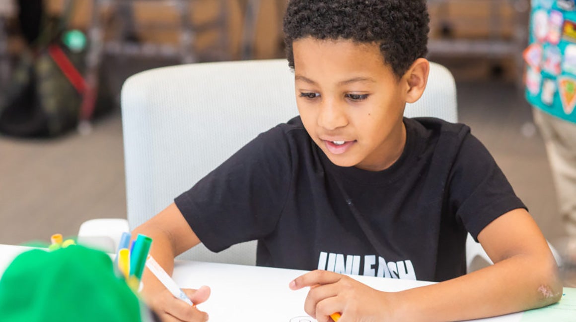 Boy sitting on the floor doing schoolwork with a laptop at home