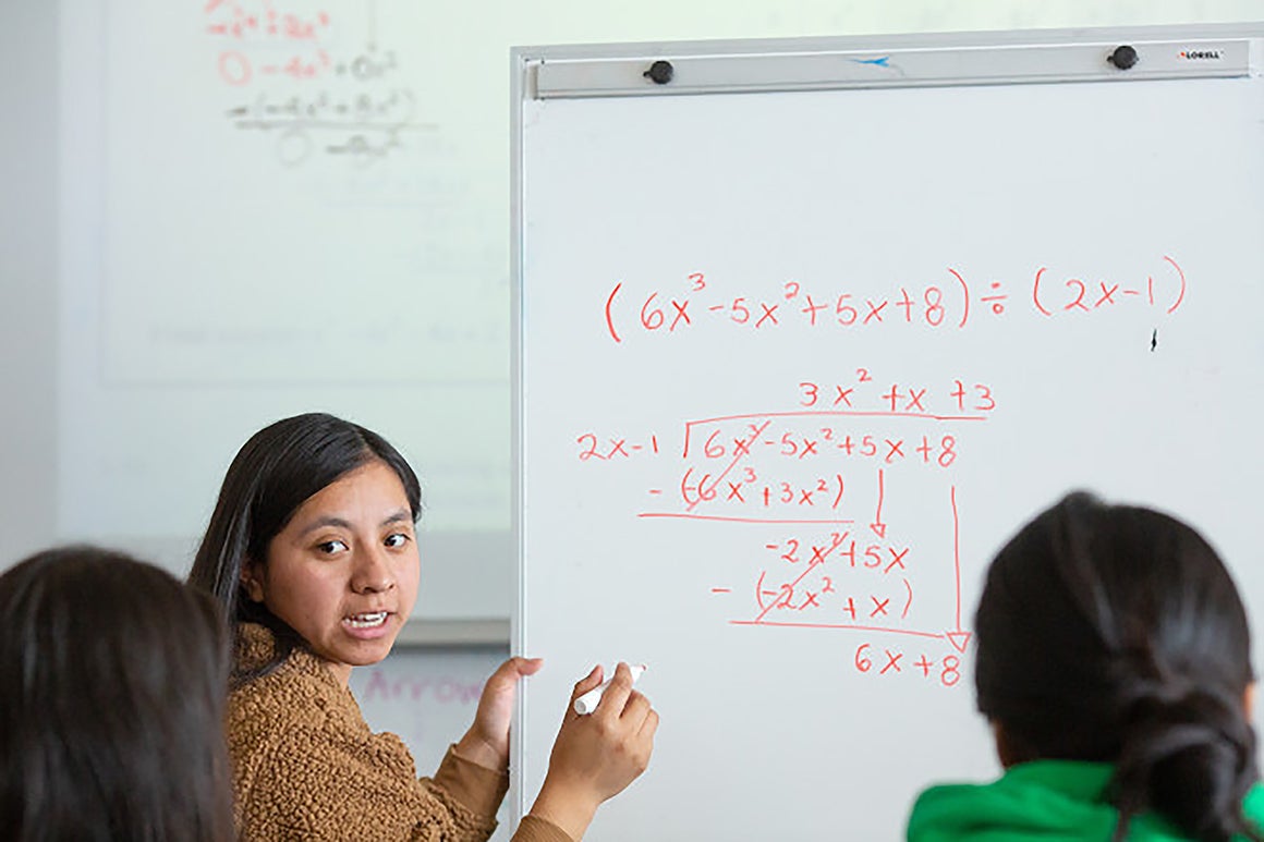 Teacher and student working through math equations on a whiteboard