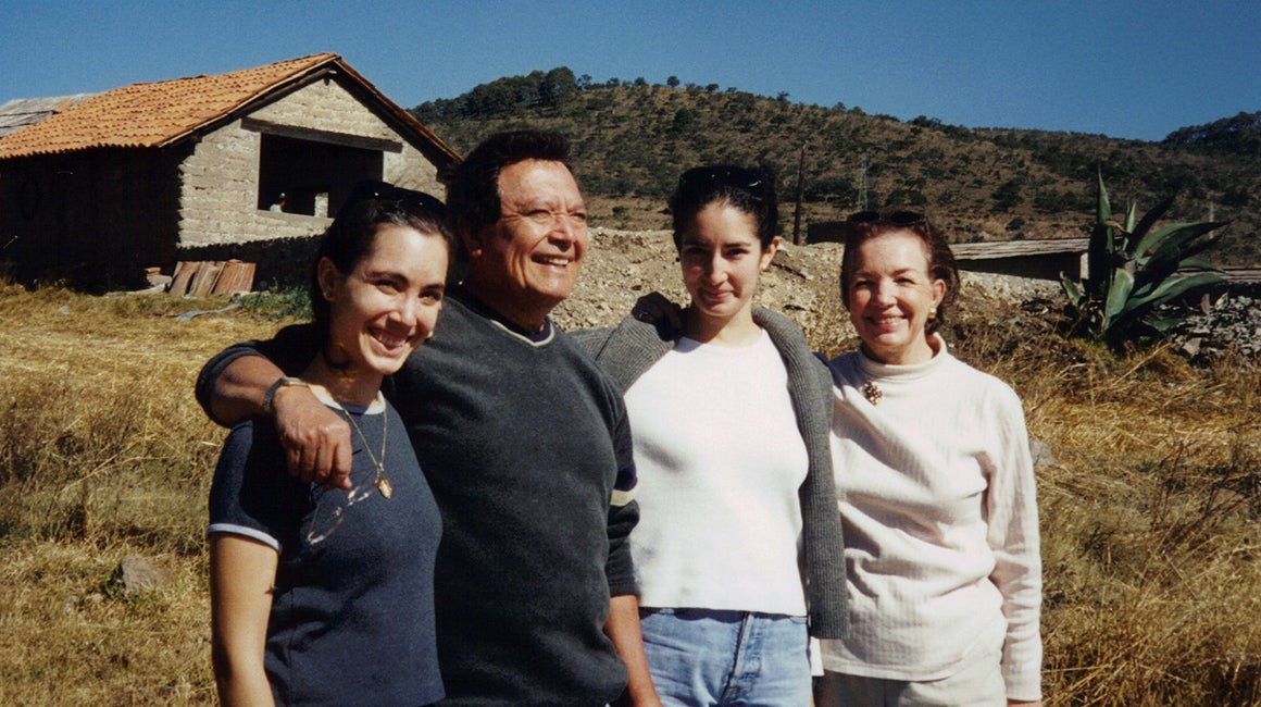 Three people embracing outdoors in a rural setting