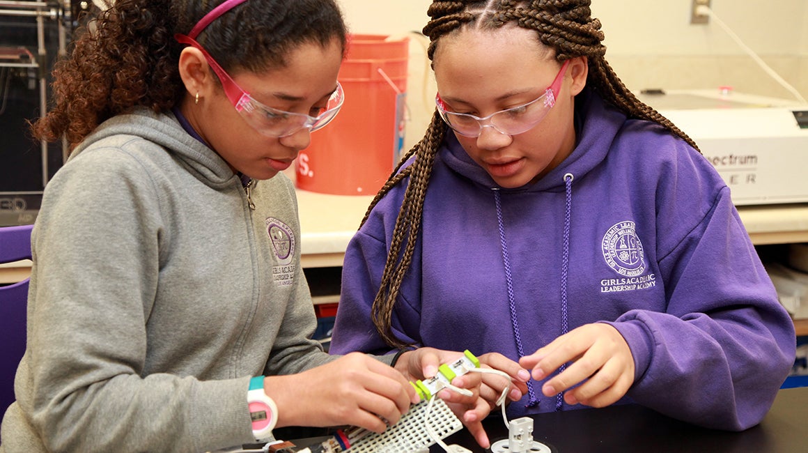 Two girls working on a craft project together outdoors