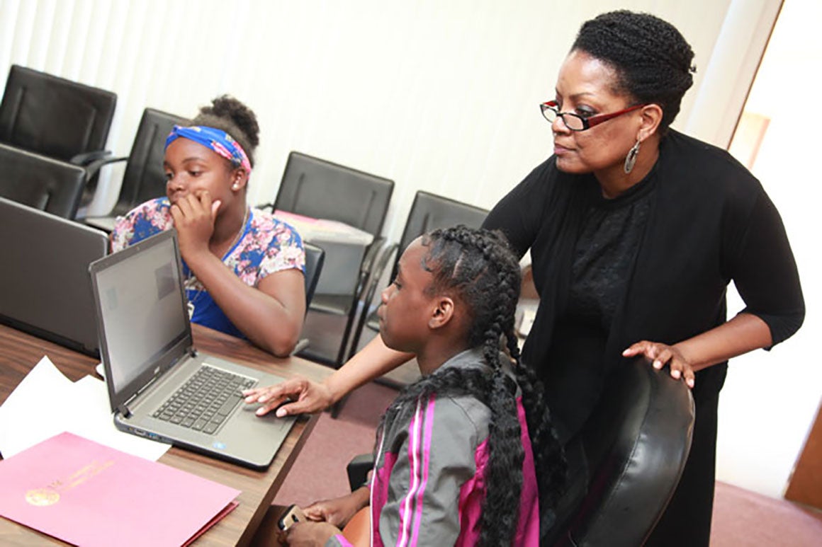 Students coding on laptops with a teacher's guidance at a code camp